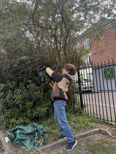A member of staff trimming hedges at Sensory Matters' premises.
